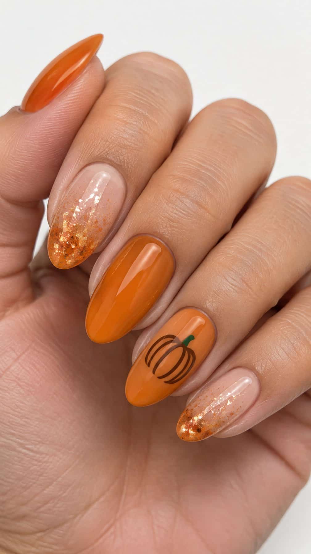Glossy pumpkin-orange and glitter gradient manicured nails