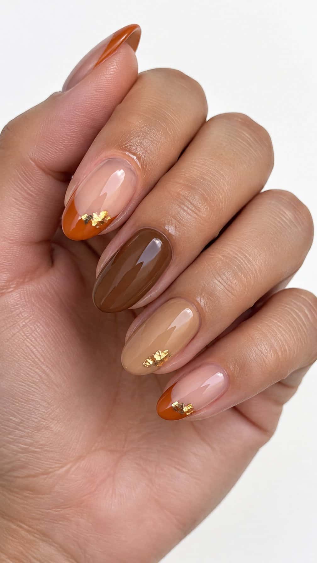 Pumpkin-orange French-tip nails, cinnamon-colored nails, and small gold accents