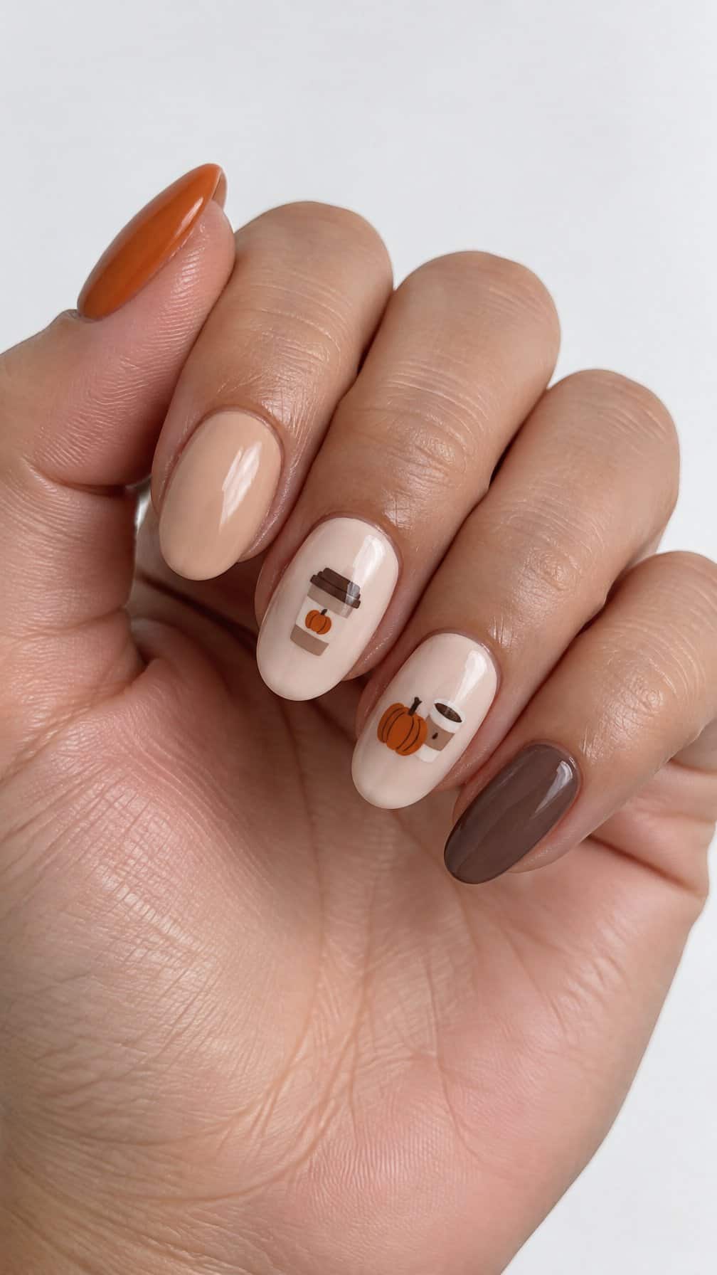 Glossy pumpkin-orange and latte-beige nails decorated with tiny coffee cup and pumpkin designs