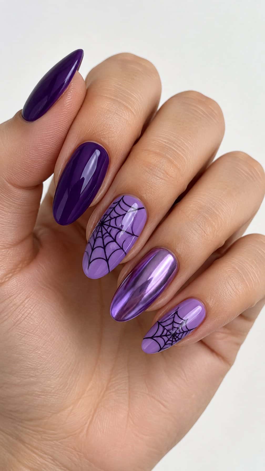Glossy purple manicure and dark spiderweb designs on accent nails
