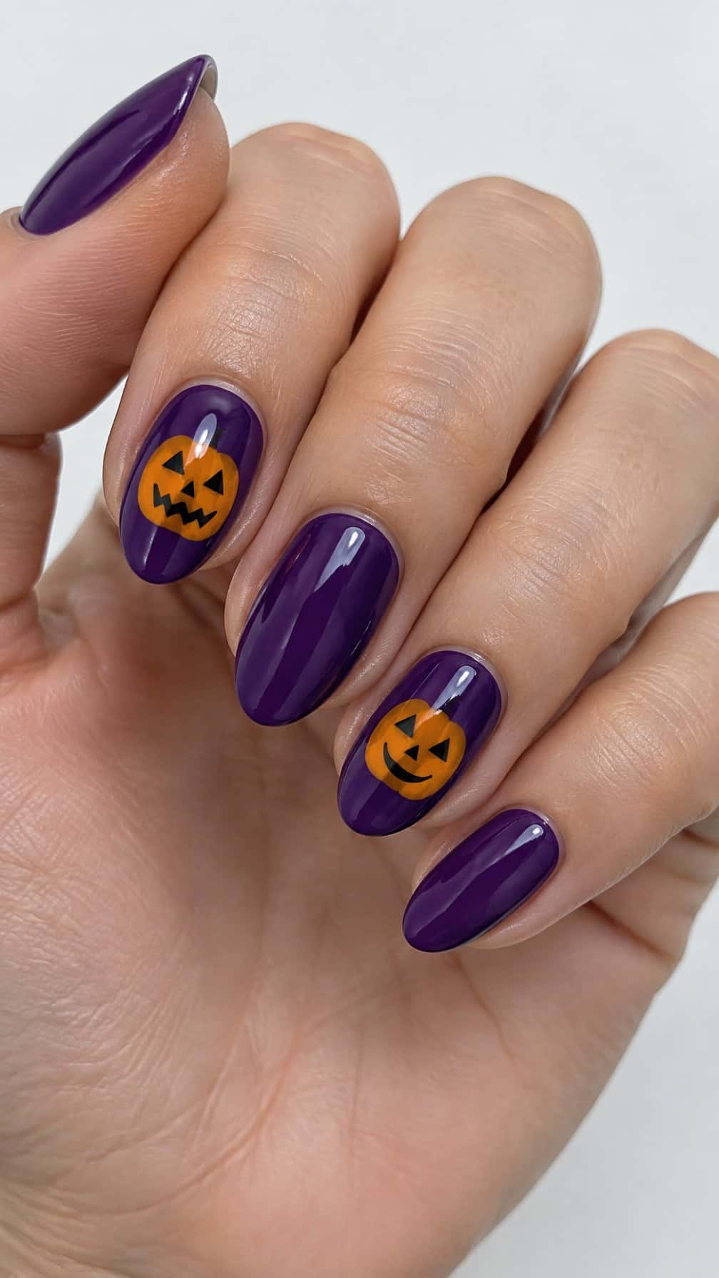 Glossy purple nails, several painted with orange jack-o'-lantern faces