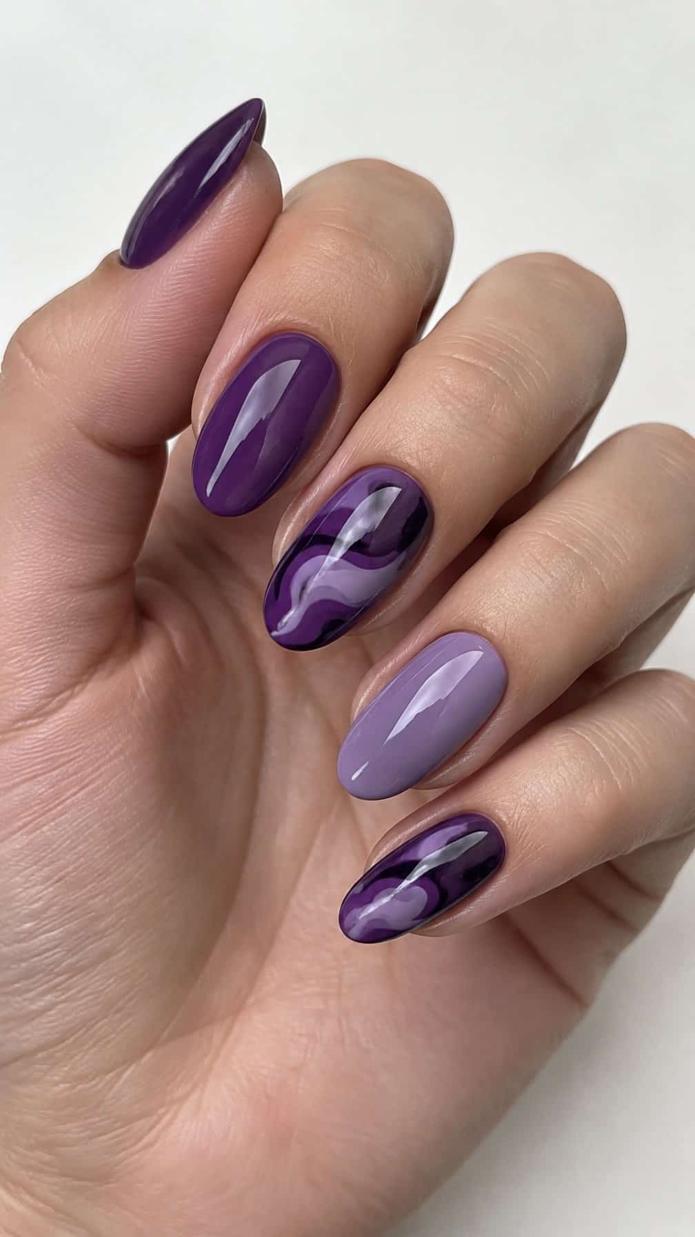 Glossy purple gel nails featuring solid colors and painted swirl designs