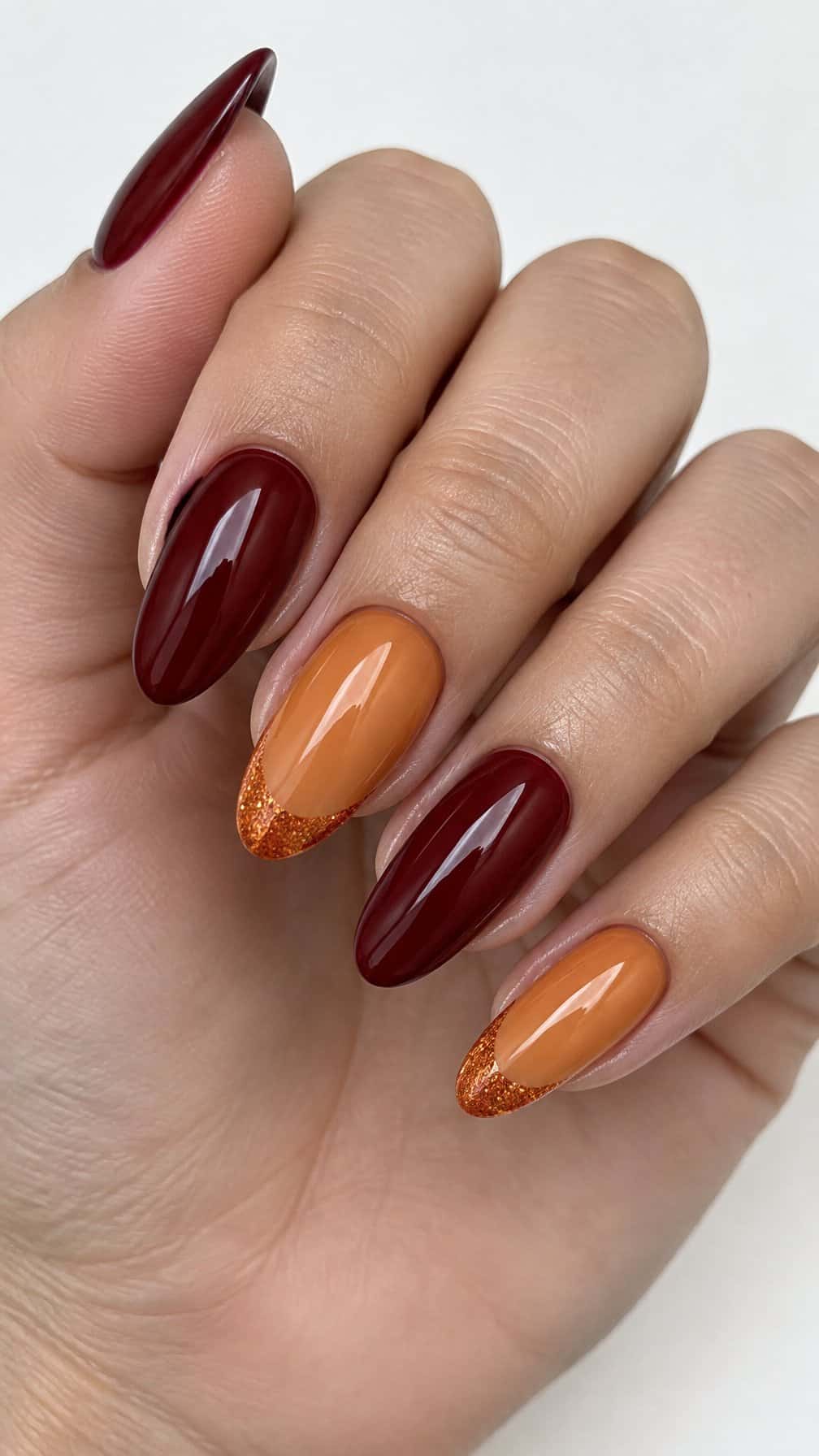Glossy deep red and pumpkin orange glitter-tip manicured nails