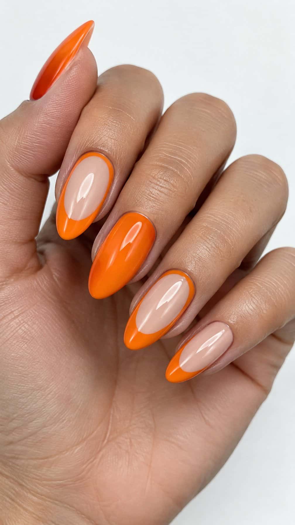 Glossy orange and nude French-tip nails
