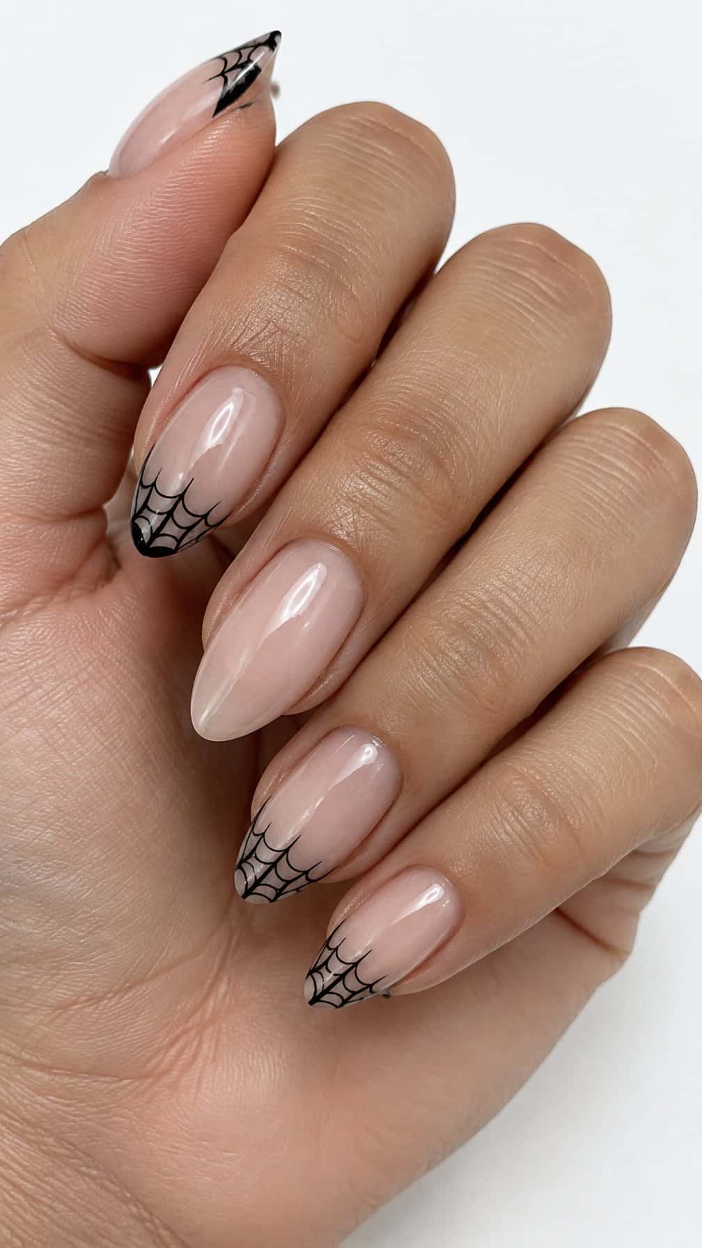 Glossy sheer nude nails and delicate black web designs on several tips