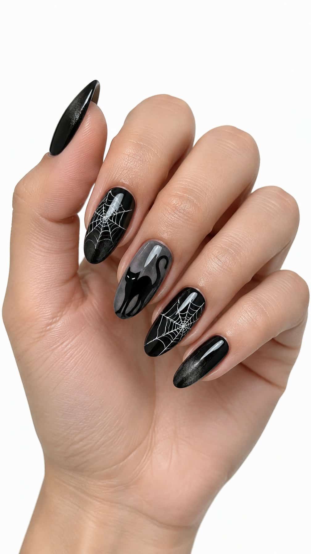 Glossy black nails decorated with white spiderwebs and a small black cat design