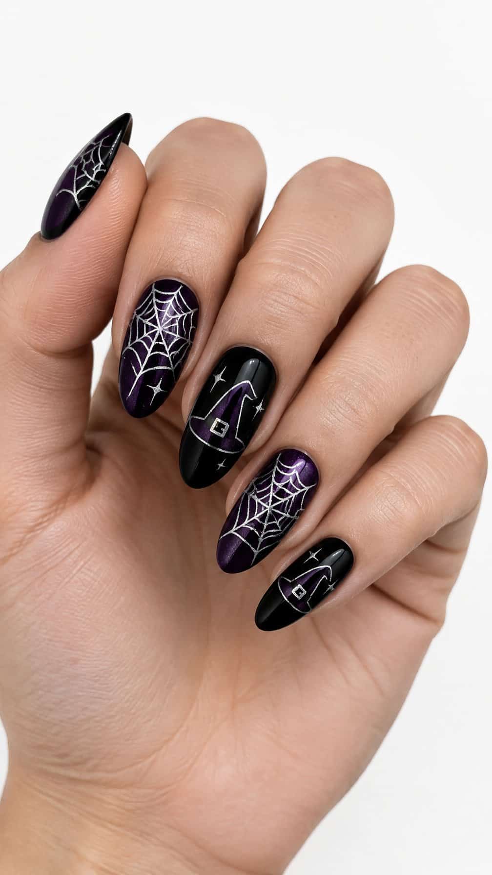 Black and purple nails decorated with white spider webs and tiny witch hats