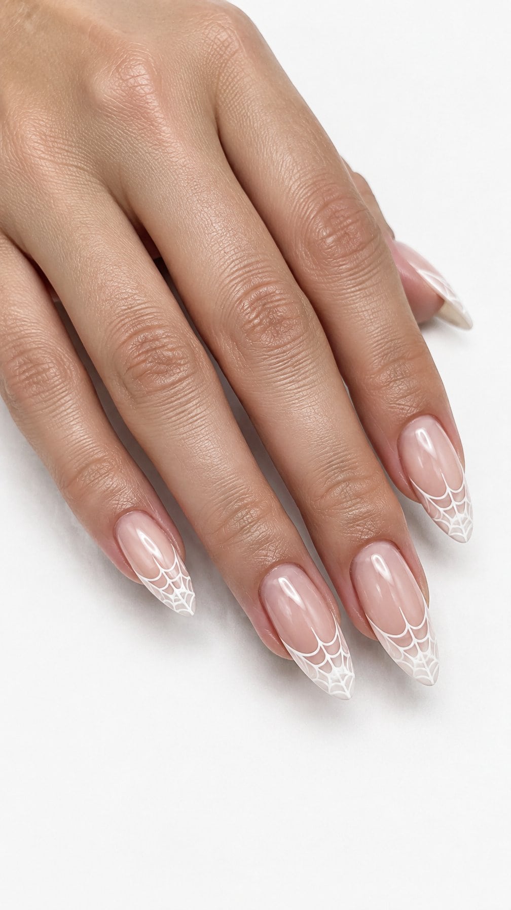 Almond-shaped nails featuring delicate white spider web French tips on a sheer nude base