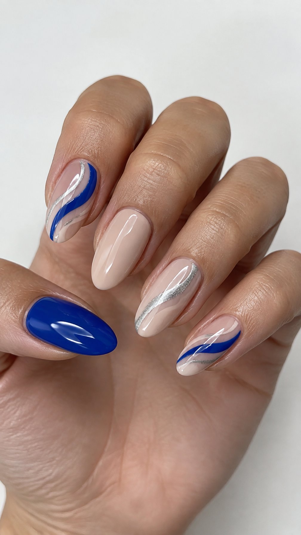 Blue, nude, and silver wave-patterned manicure