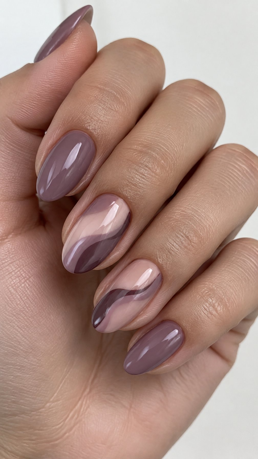 Glossy mauve nails, including solid-color nails and flowing negative-space wave designs