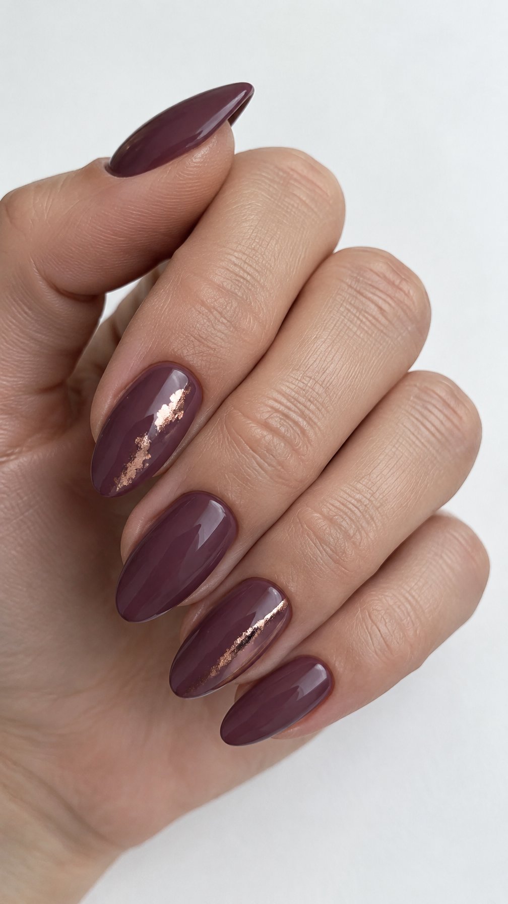 Glossy deep mauve nails and small rose gold accents