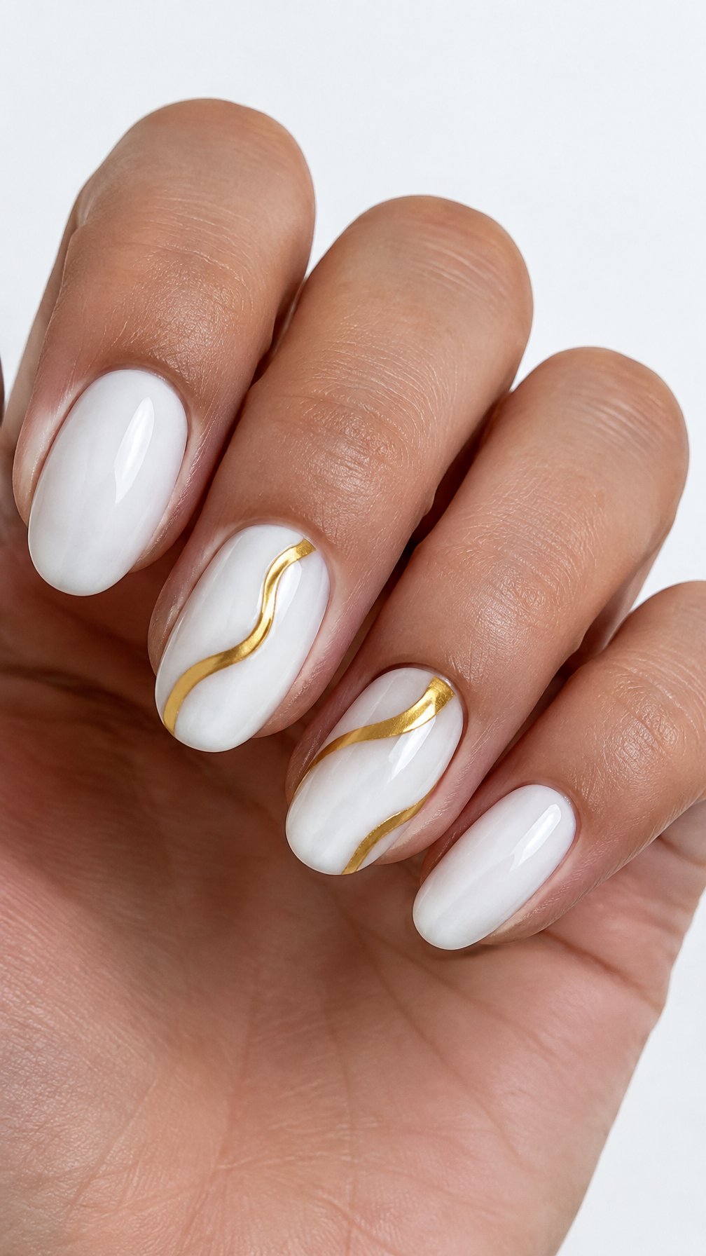 Glossy white nails decorated with simple gold wave patterns