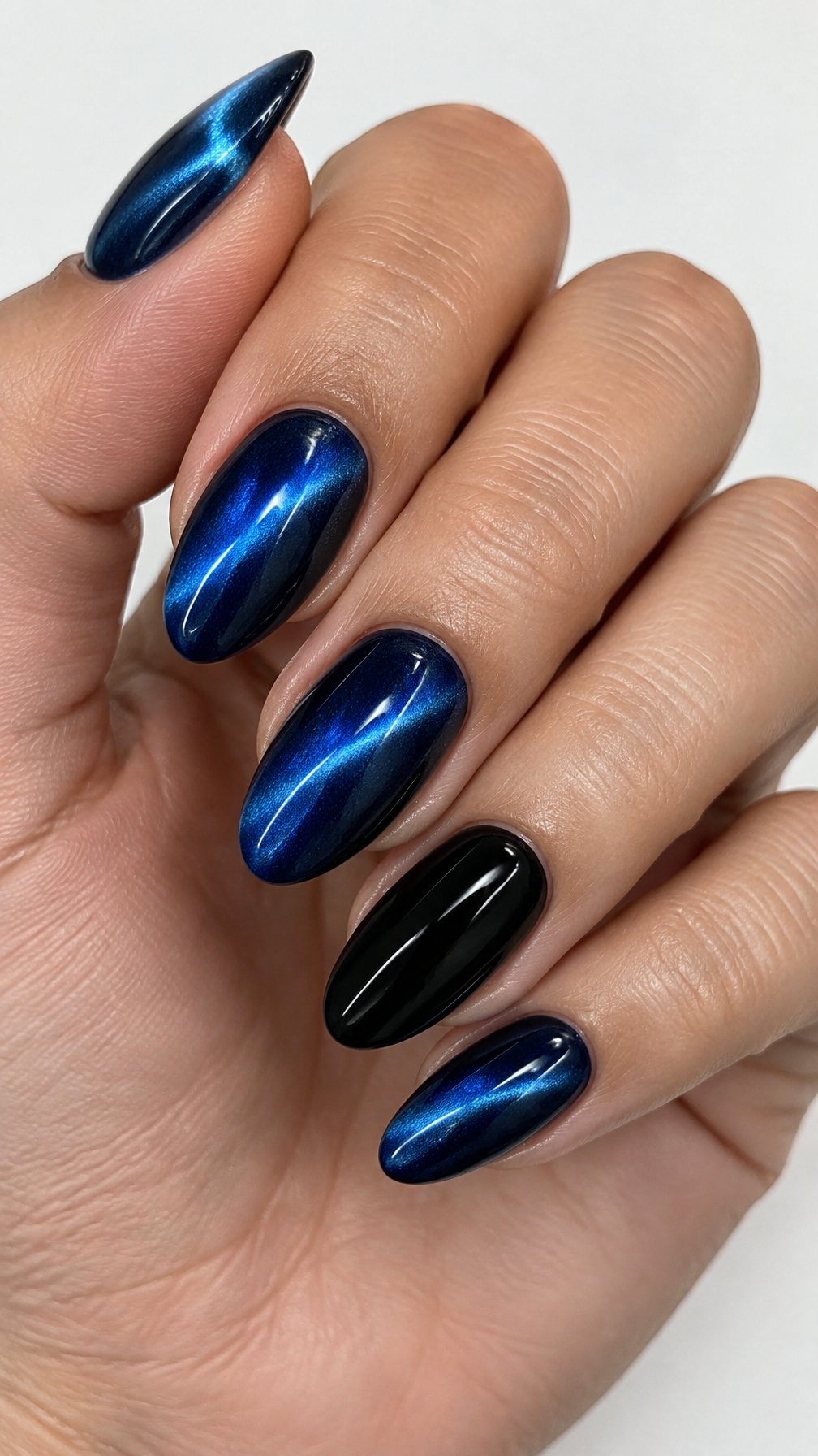 Glossy sapphire-blue cat-eye nails and black accent nails