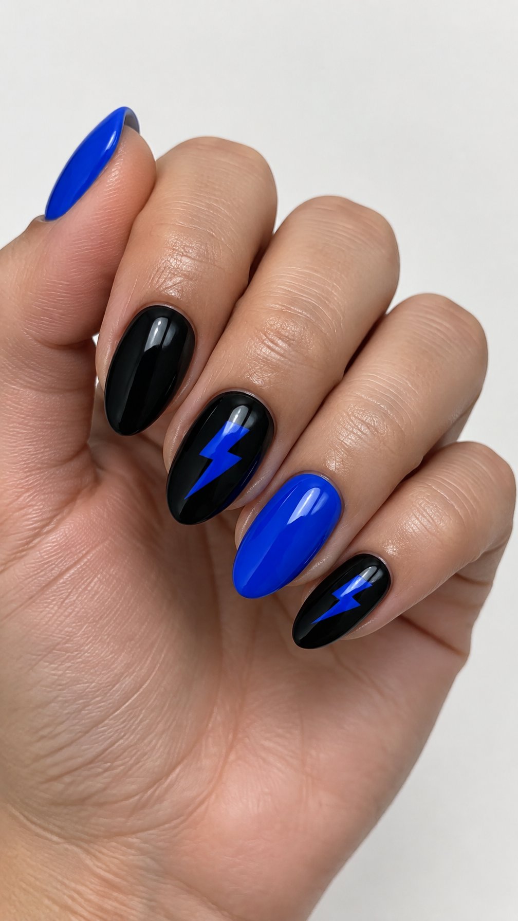 Glossy black and cobalt-blue gel nails, including simple blue lightning bolt designs, photographed