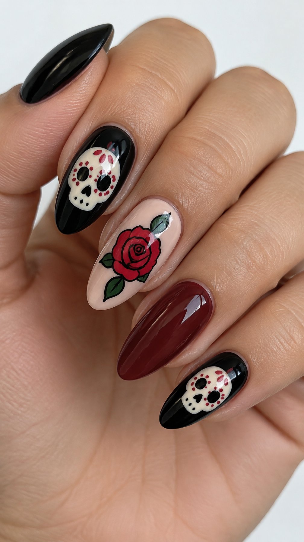 Glossy sugar skull and rose nail art with several solid-color nails