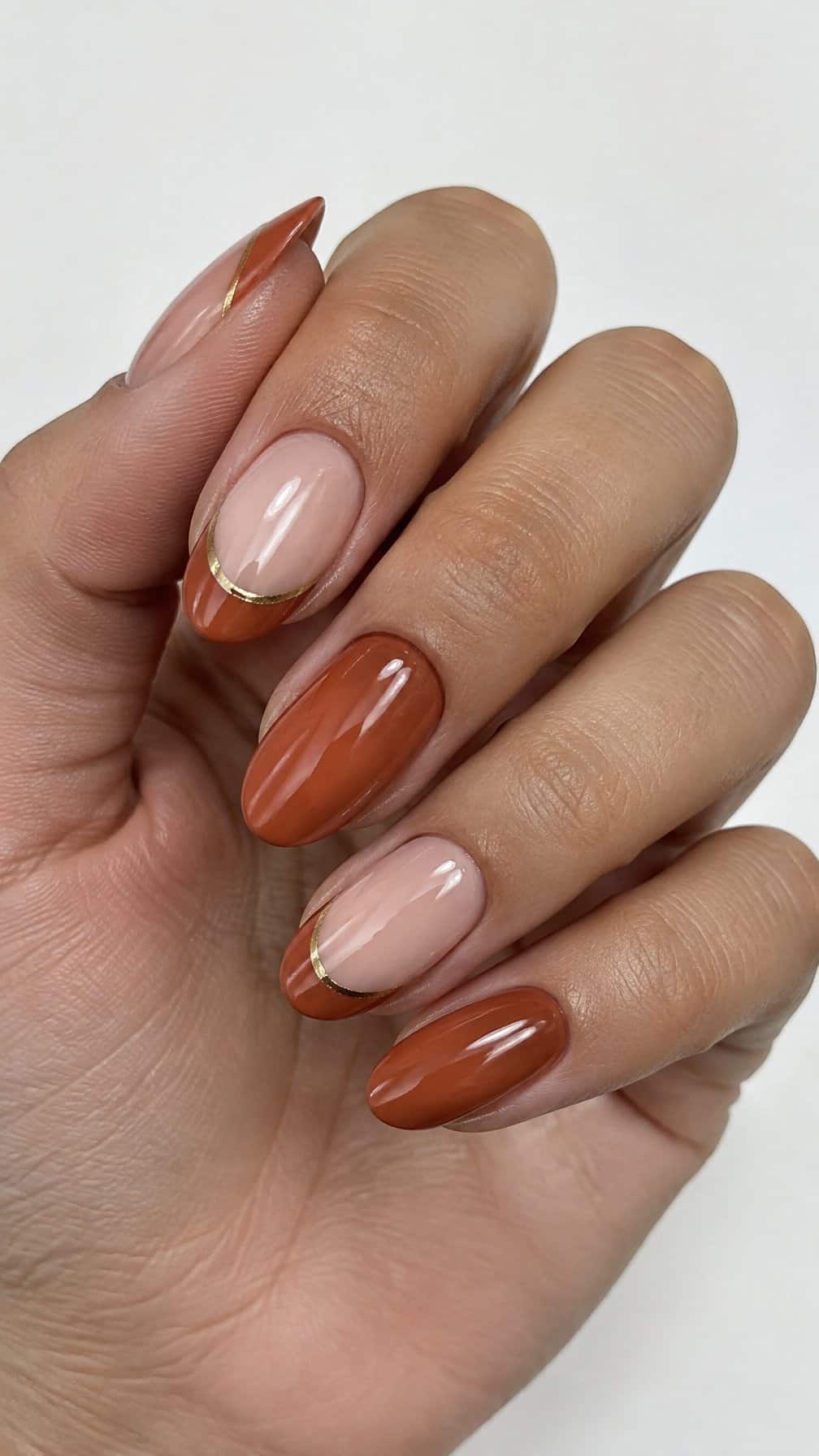 Glossy terracotta French-tip nails accented by thin gold lines