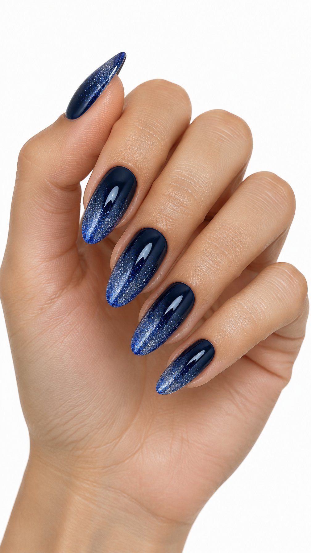A single hand displays almond-shaped nails painted with a midnight blue glitter gradient.