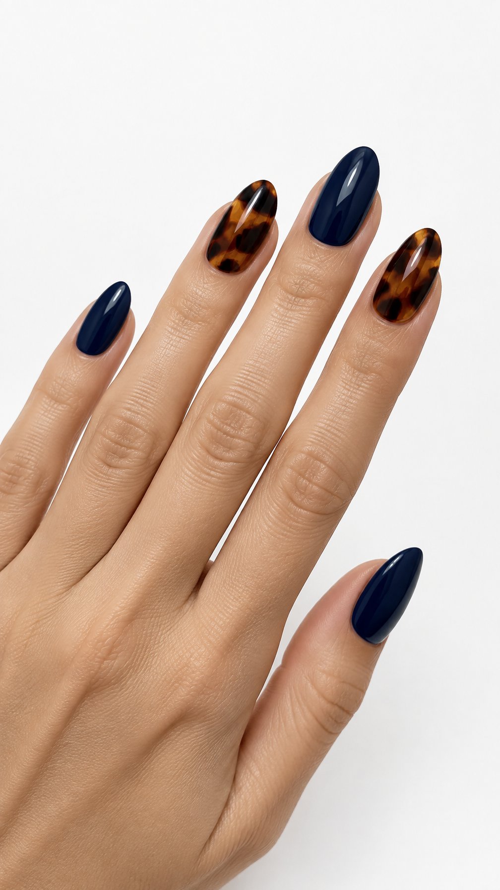 A single hand with glossy midnight blue nails and tortoiseshell accent nails on a white background.
