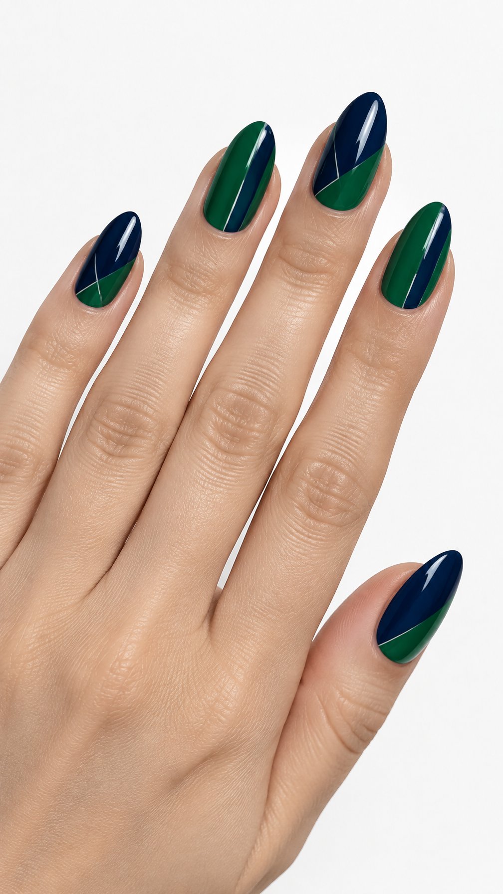 A single hand displays glossy almond-shaped nails painted in midnight blue and emerald green geometric blocks against a white background.