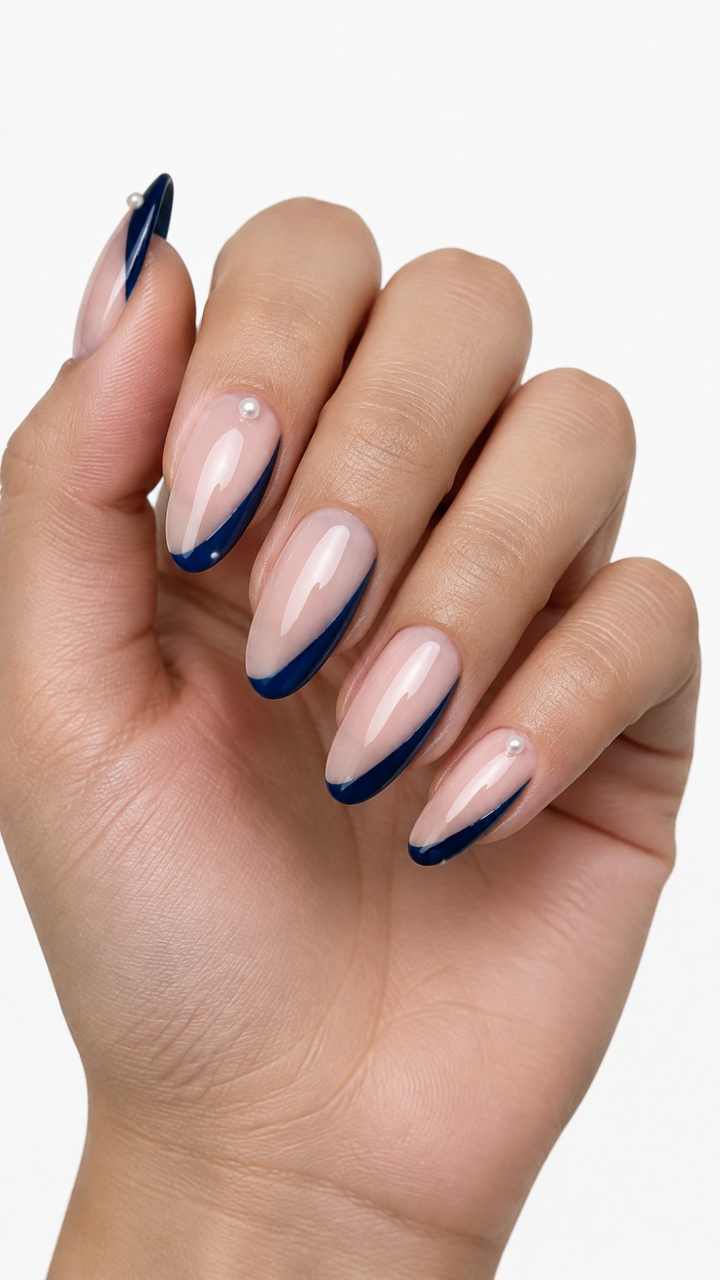 A single hand with almond-shaped nails featuring midnight blue side French tips and small pearl accents on a white background.