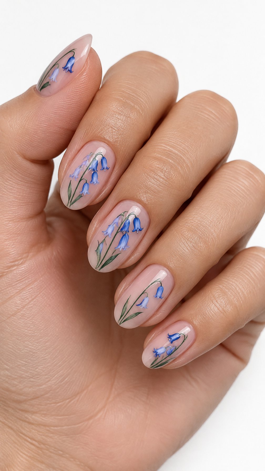 A single hand with sheer pink nails decorated with delicate bluebell flowers on a white background.