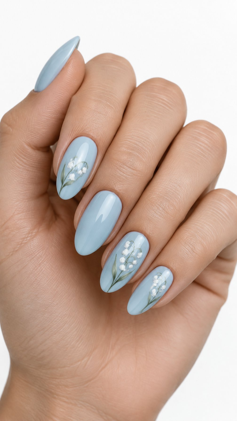 A single hand with robin’s egg blue nails decorated with delicate white lily-of-the-valley flowers against a white background.