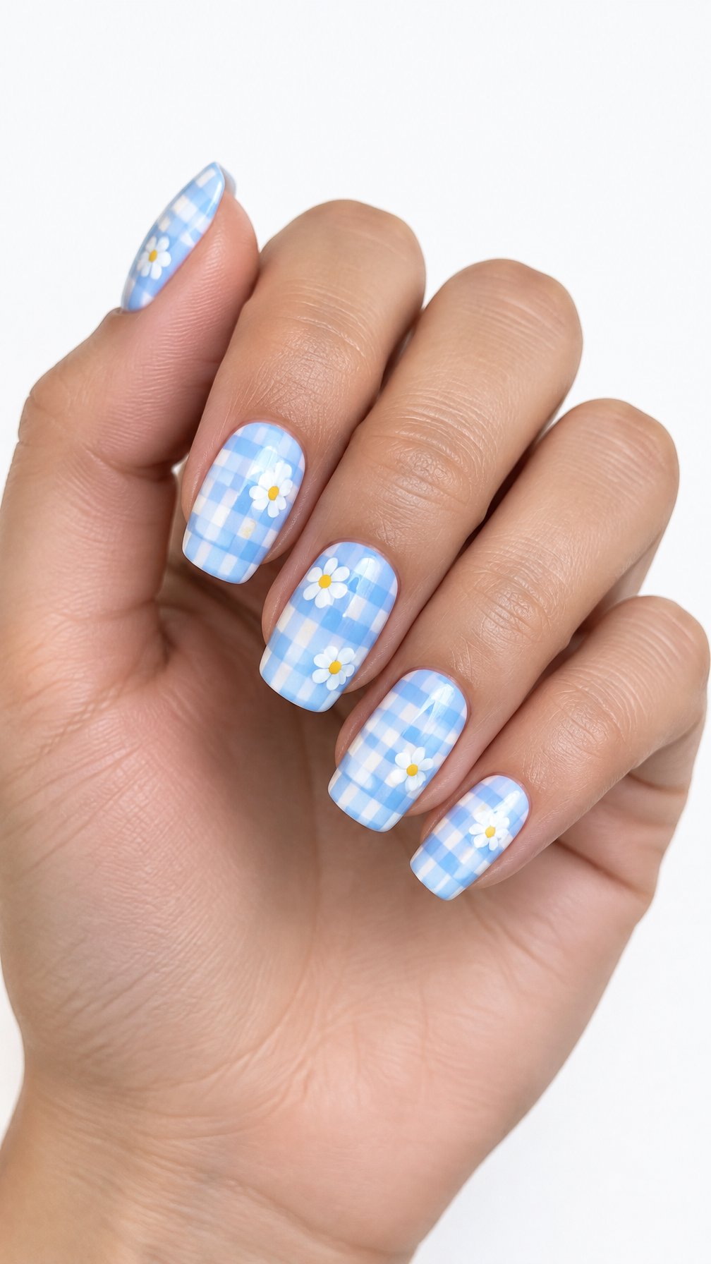 A single hand with glossy pastel blue gingham nails decorated with small white daisies against a white background.