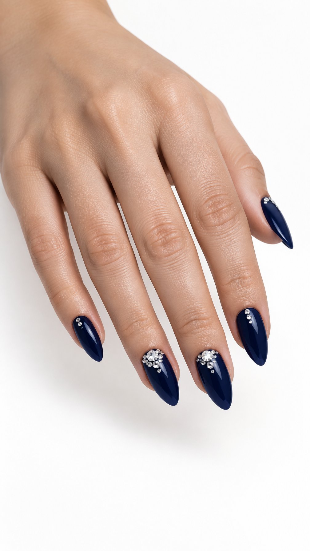 A single hand with glossy midnight blue almond-shaped nails decorated with small crystal clusters on a white background.