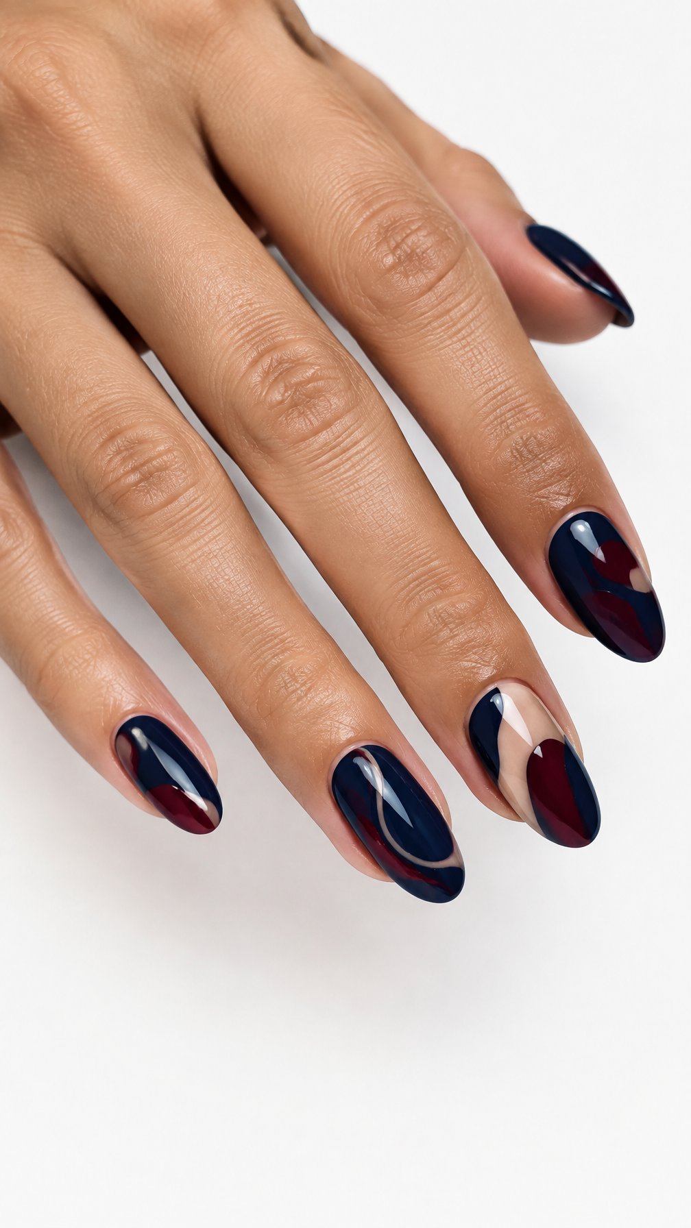 A single hand with glossy midnight blue and burgundy abstract nail art against a white background.