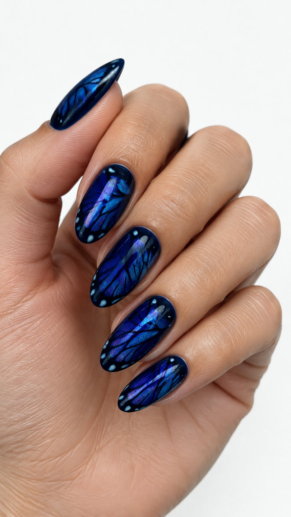 A single hand with glossy midnight blue butterfly-inspired designs on its manicured nails against a white background.