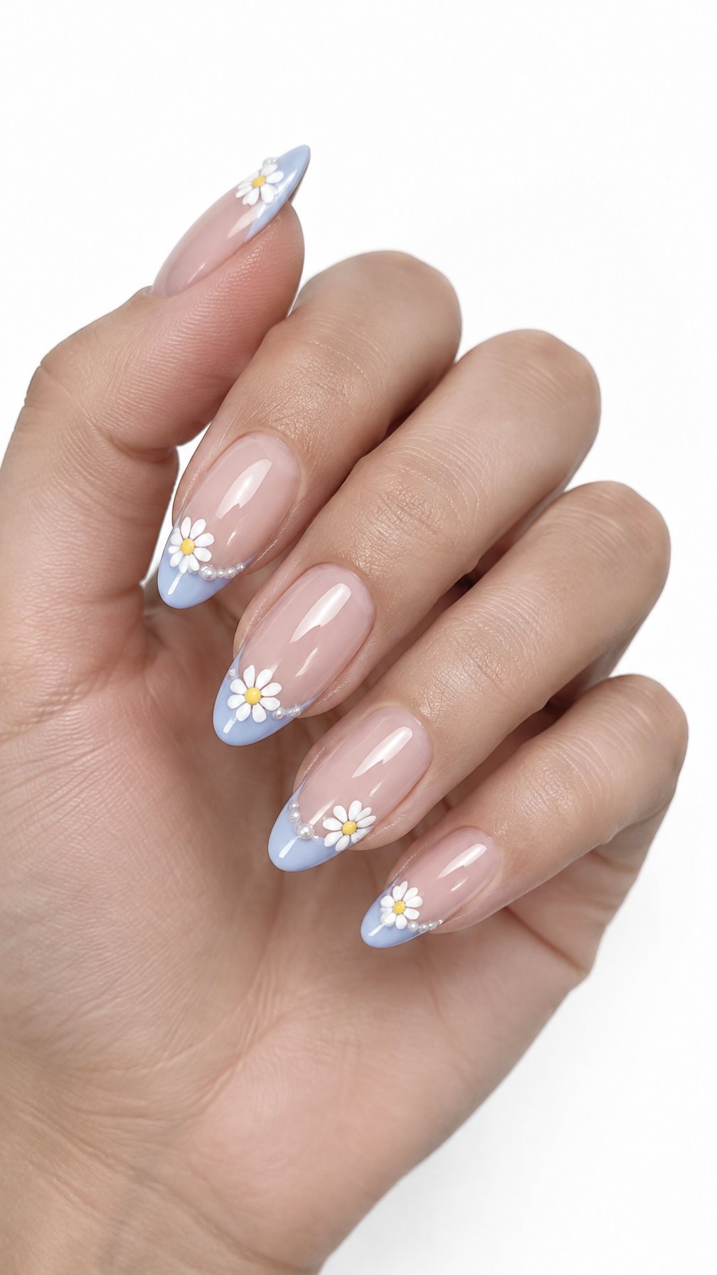 A single hand with blue French-tip nails decorated with small white daisies and pearl accents on a white background.