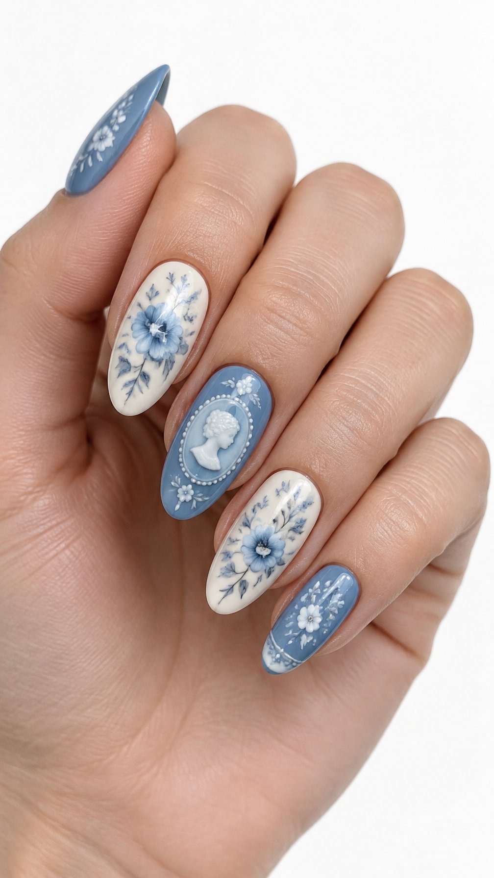 A single hand with detailed blue and ivory floral cameo nail art on almond-shaped nails against a white background.