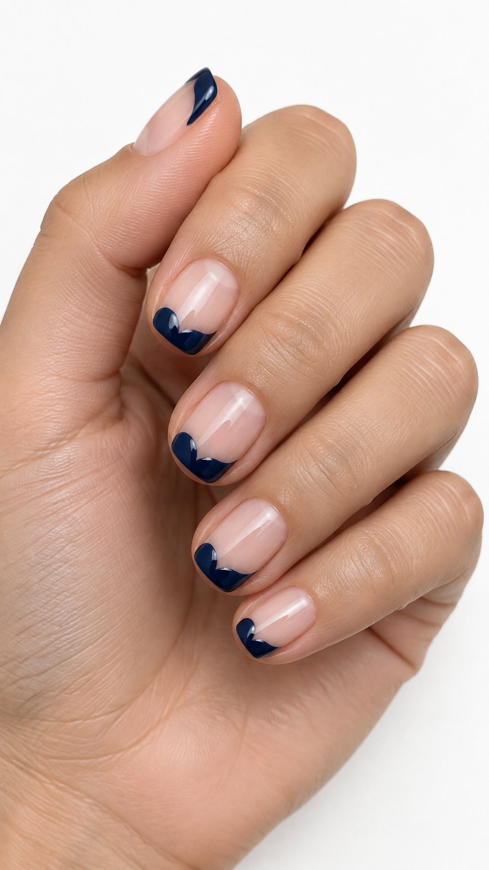 A single hand with short nails featuring glossy midnight-blue heart-shaped tips on a white background.