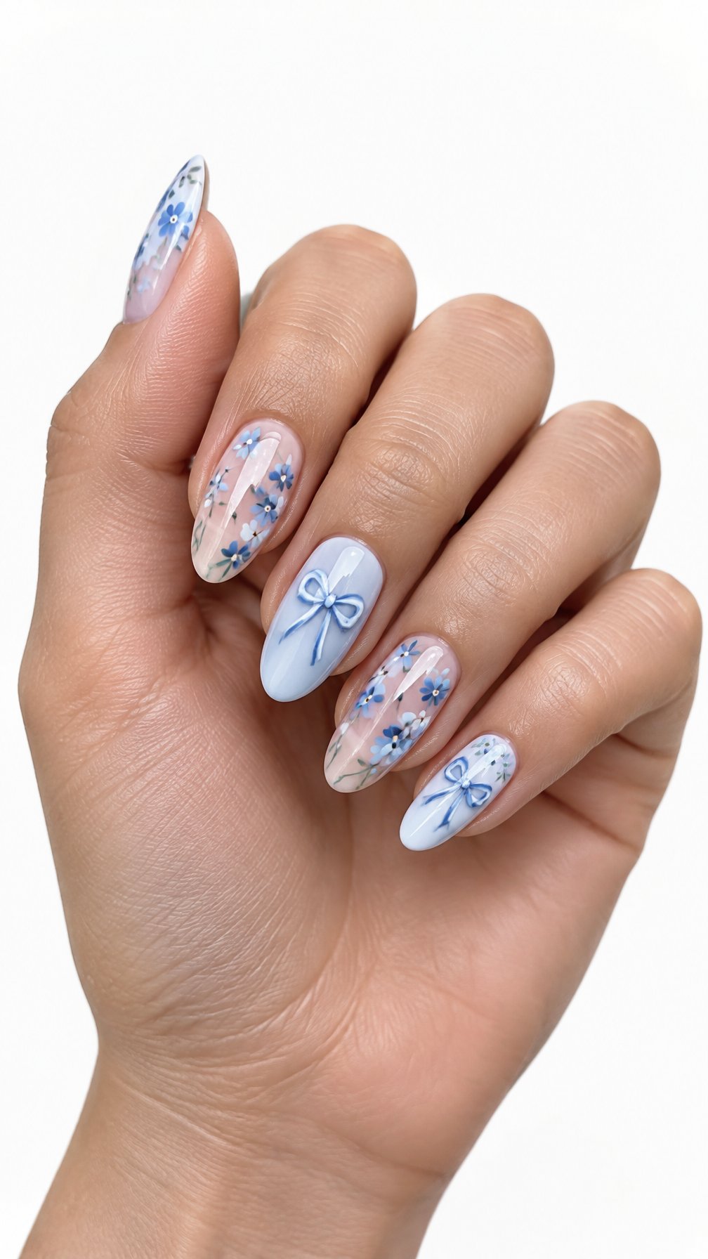 A single hand with glossy blue floral nails and small bow designs rests against a white background.