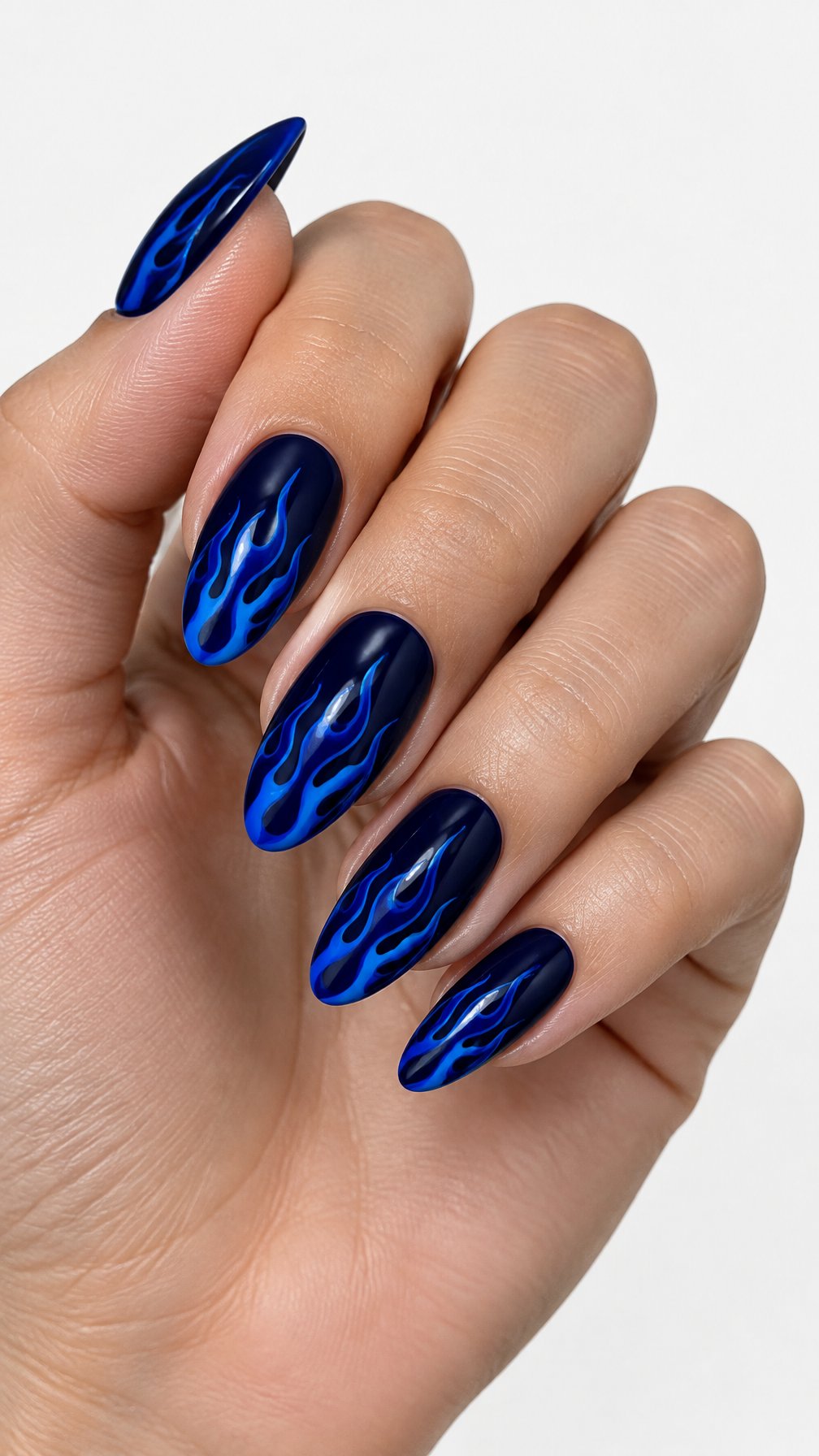 A single hand with glossy midnight-blue nails decorated with cobalt-blue flame designs against a white background.