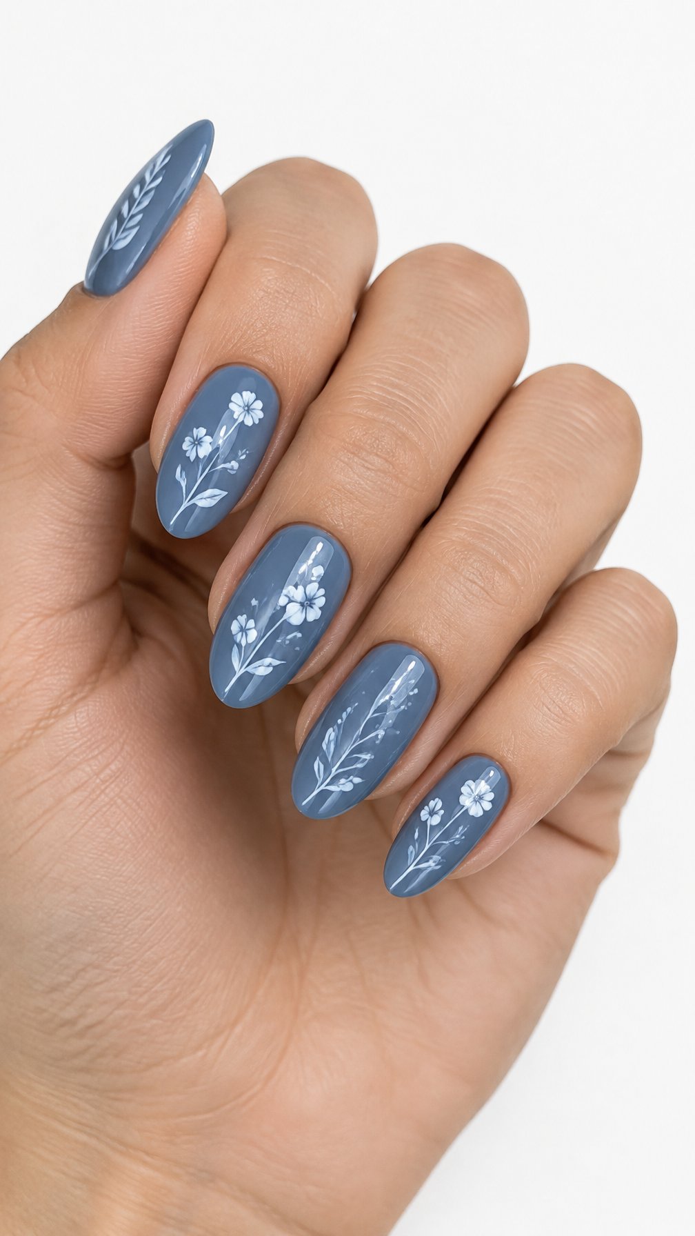 A single hand with glossy steel-blue nails decorated with delicate white botanical designs against a white background.