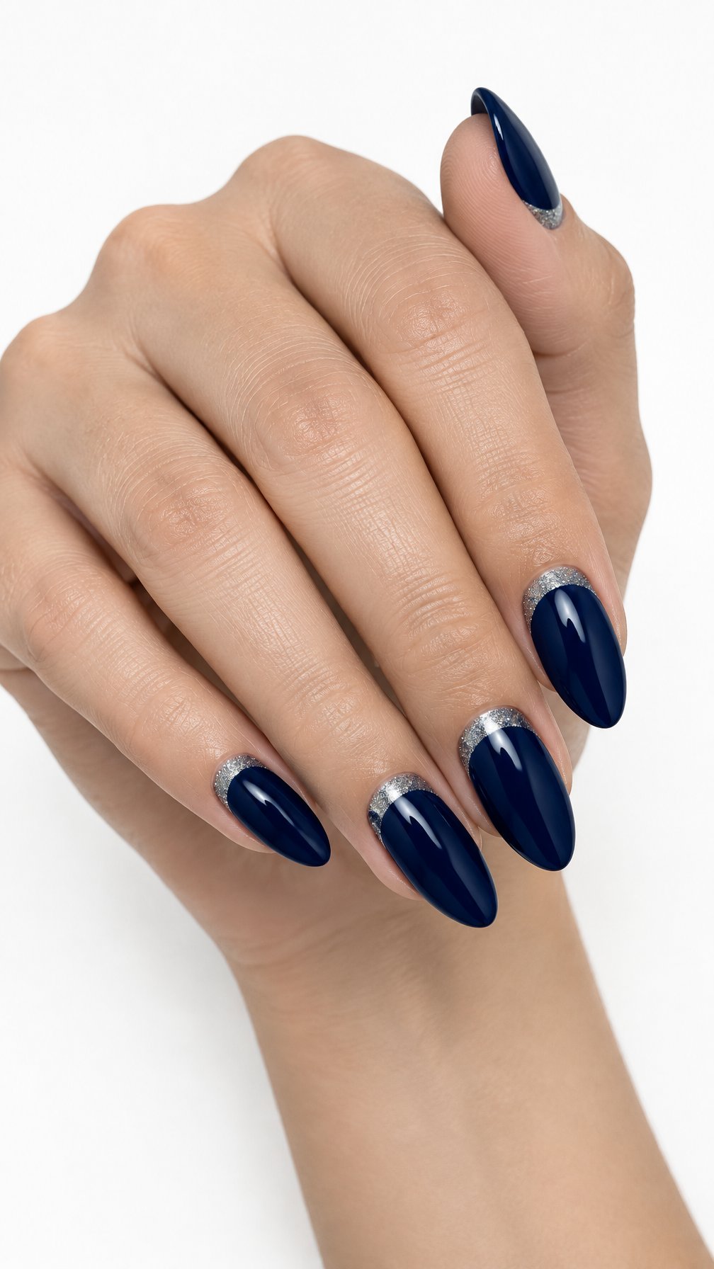 A single hand with almond-shaped midnight blue nails featuring curved silver glitter accents near the cuticles on a white background.