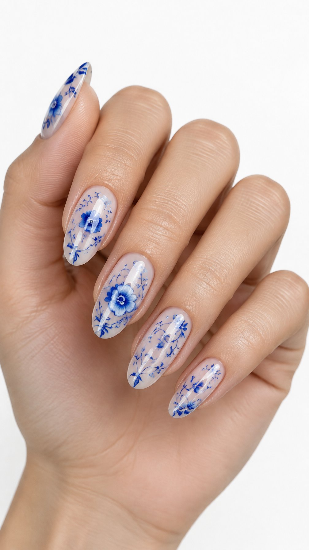 A single hand with sheer nude nails decorated with delicate blue floral lace designs.