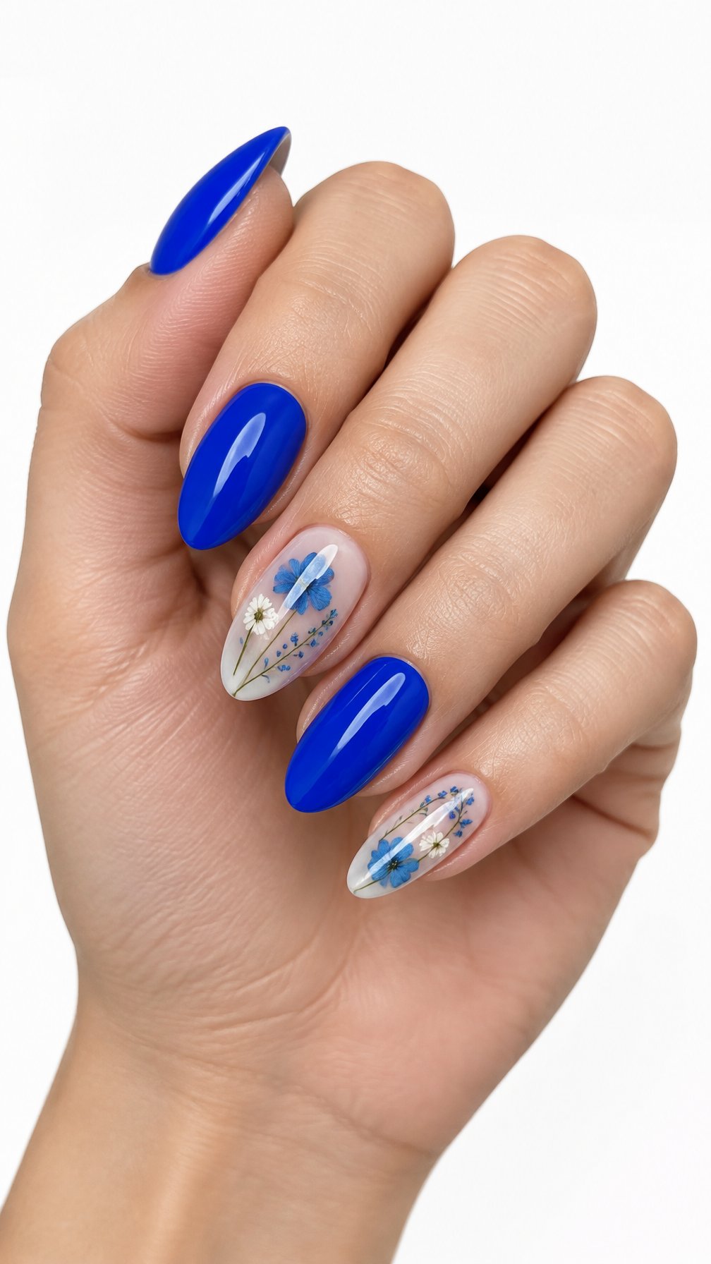 A single hand displays cobalt blue manicured nails with delicate pressed flowers on a white background.