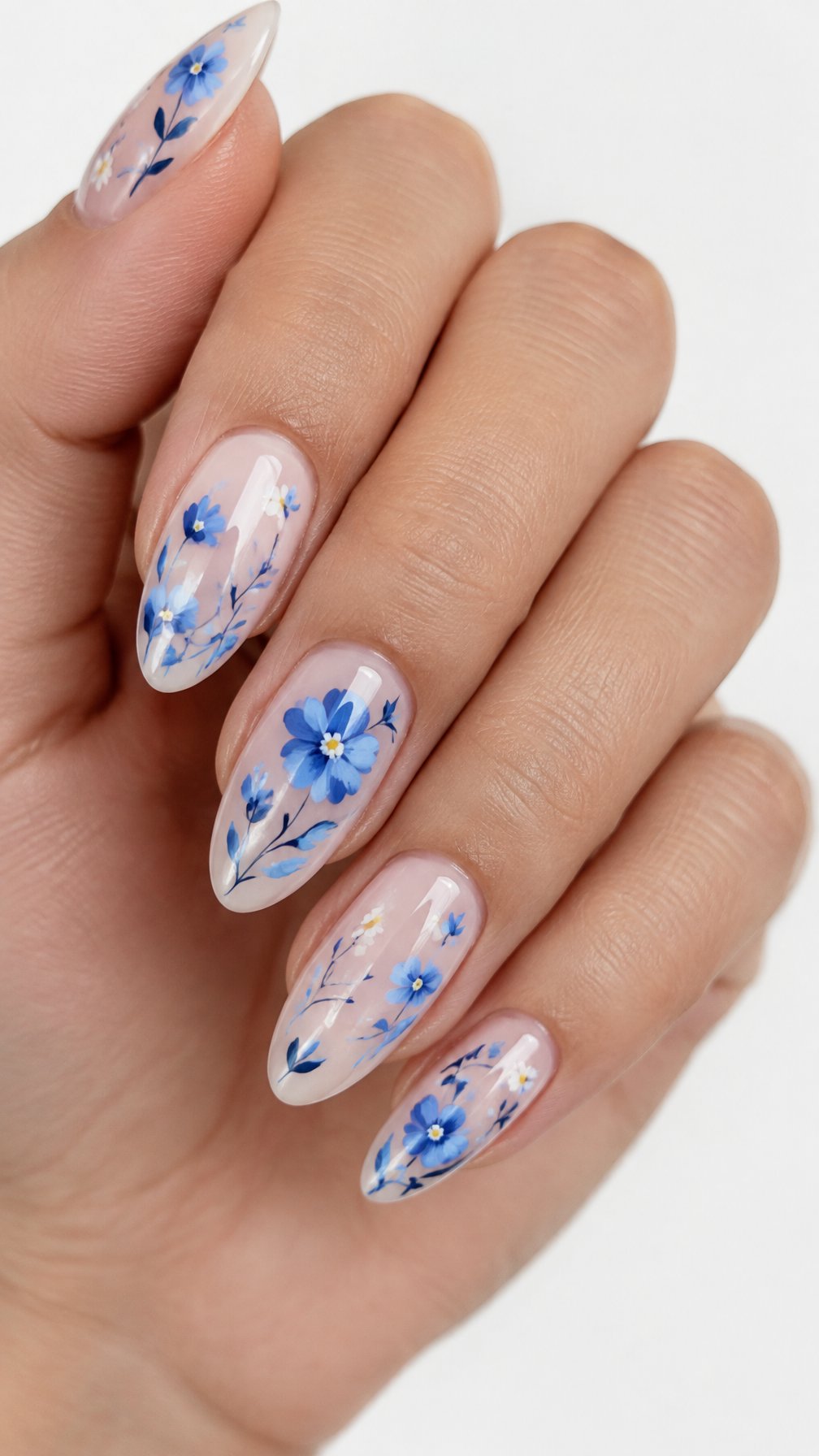 A single hand with glossy almond-shaped nails decorated with delicate blue flower designs rests against a white background.