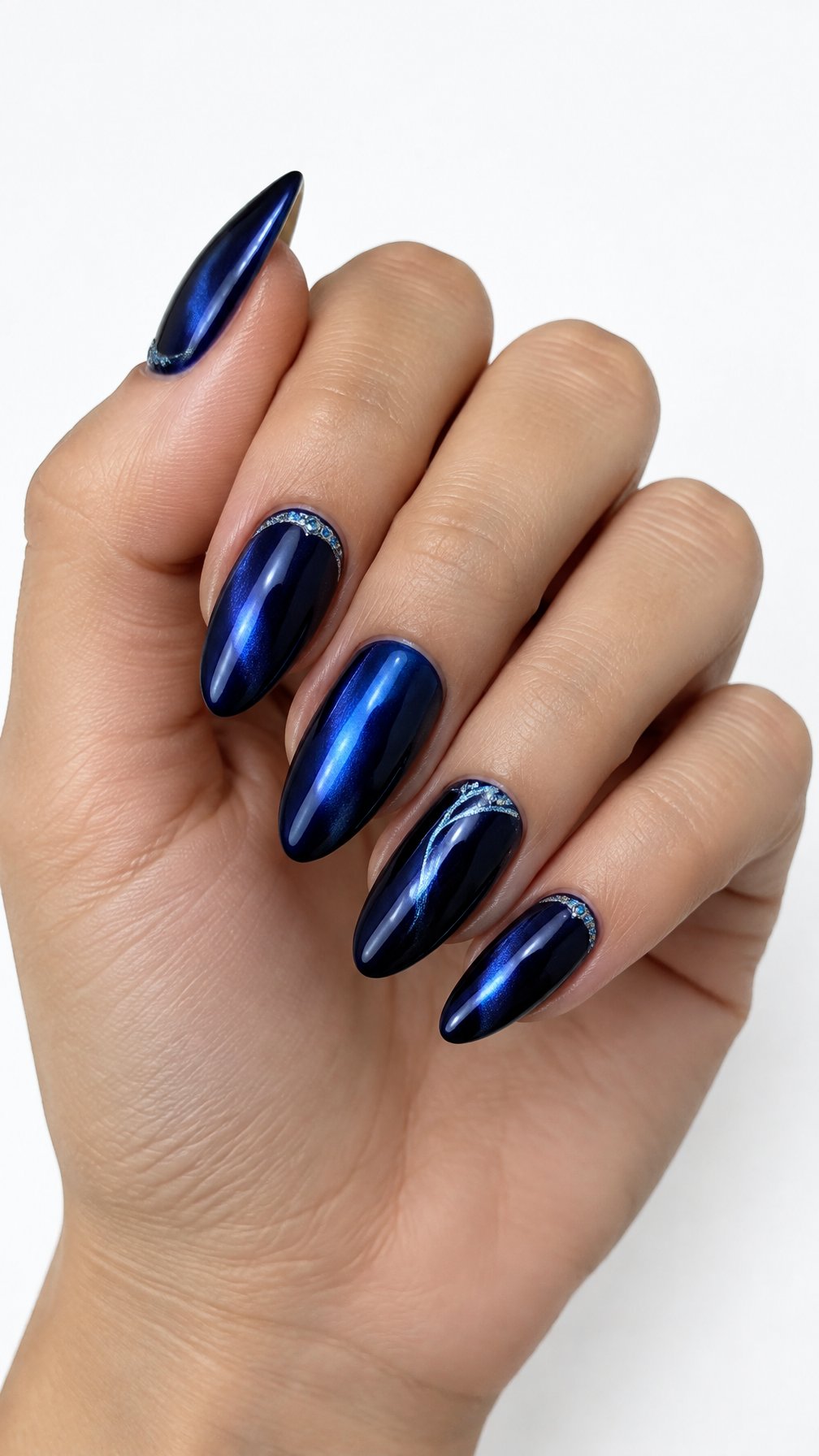 A single hand displays glossy midnight blue chrome almond-shaped nails against a white background.