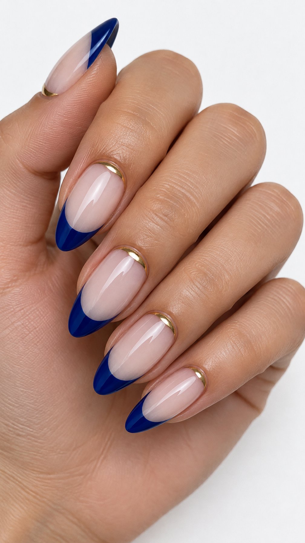 One hand with glossy sapphire-blue French tip nails and small gold half-moon accents against a white background.