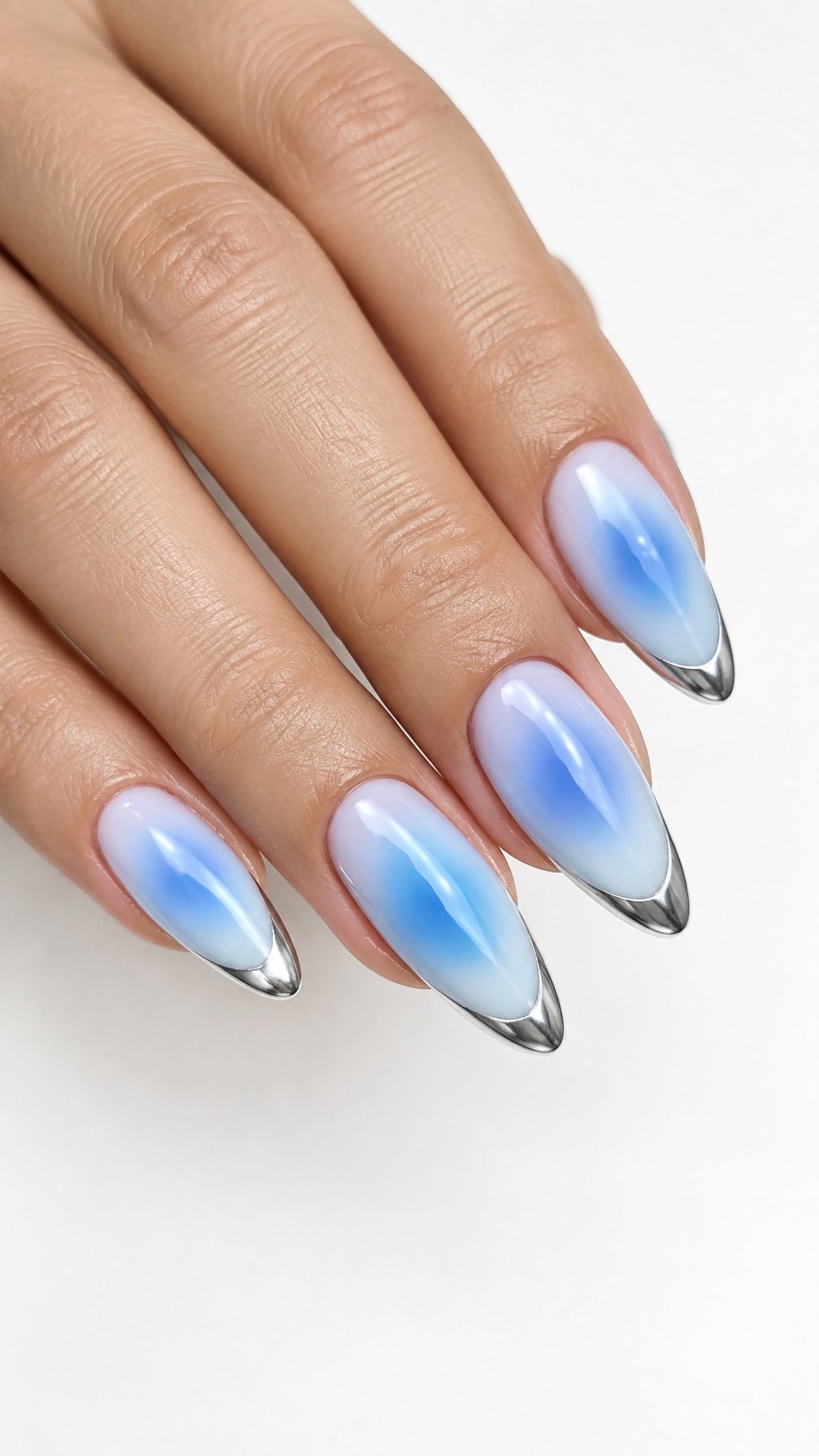 A single hand with almond-shaped blue aura nails and shiny silver chrome tips against a white background.