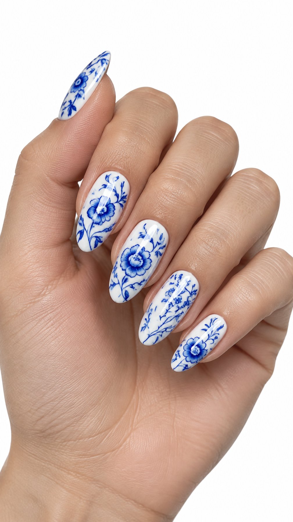 A single hand displays glossy blue-and-white floral porcelain-inspired nail art against a white background.