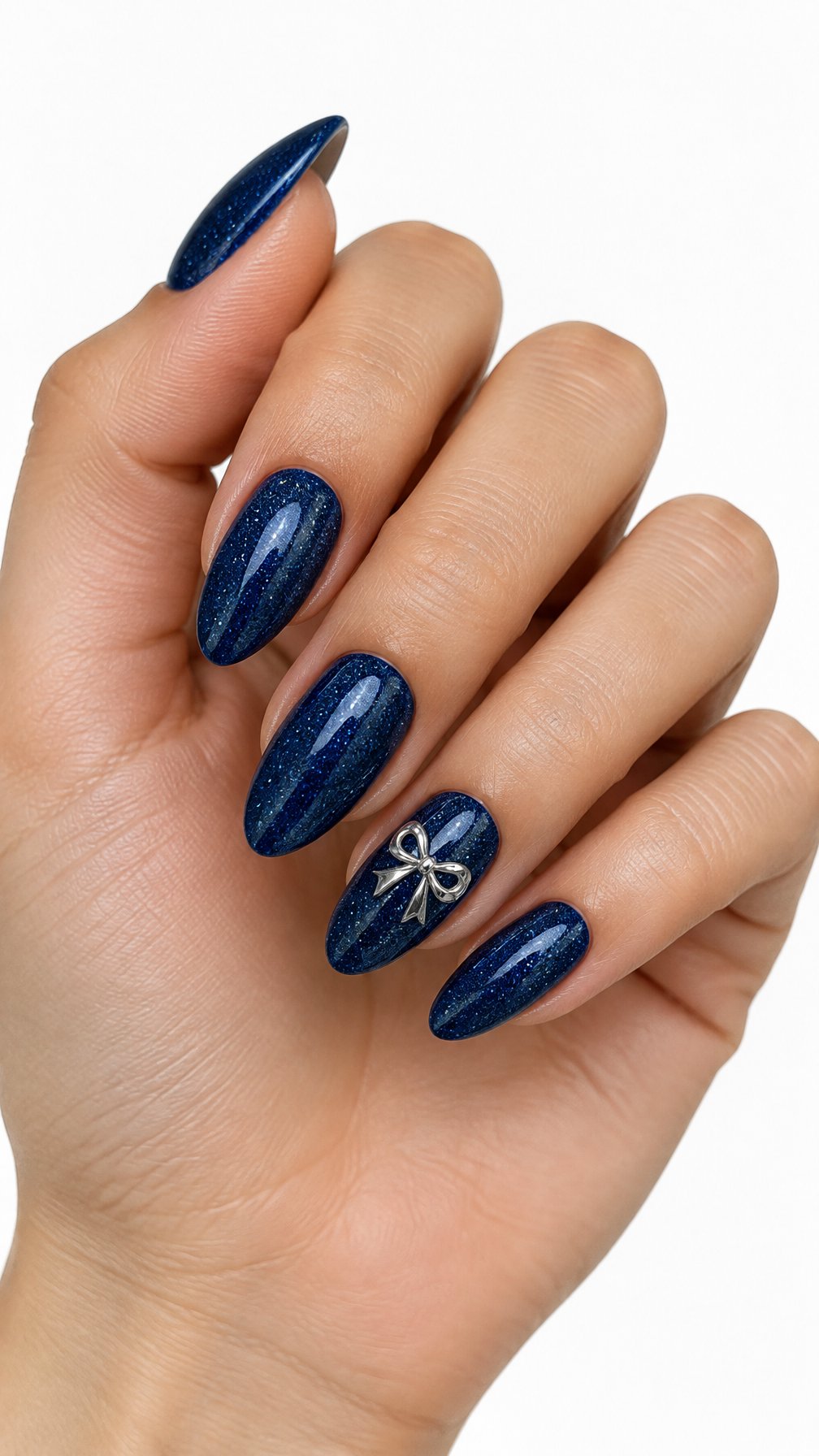 A single hand with glossy navy glitter nails and a silver bow accent on one nail against a white background.