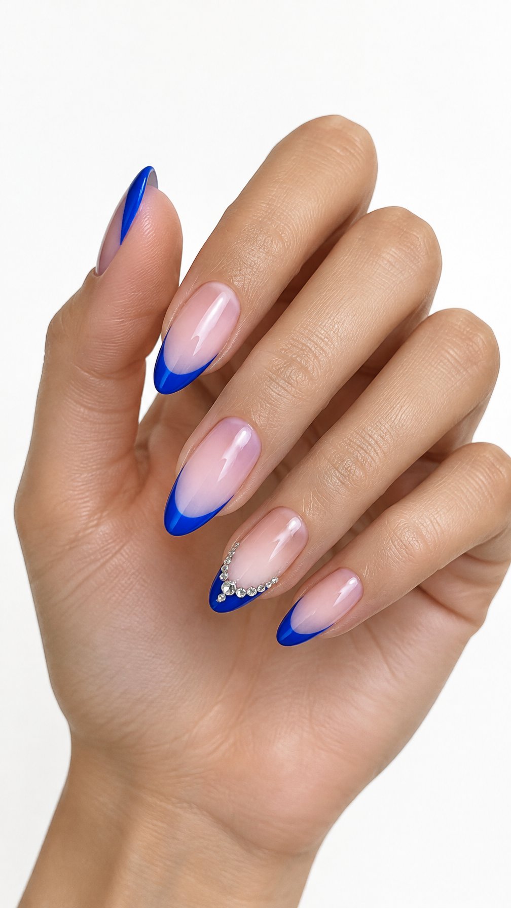 A single hand displays glossy blue French-tip nails with crystal accents on the ring fingers against a white background.