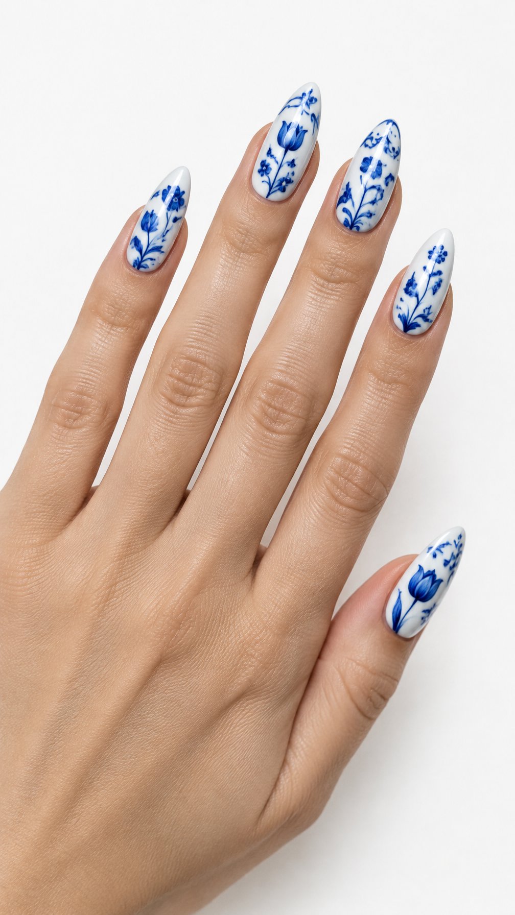 A single hand with long almond-shaped nails painted white and decorated with intricate blue floral designs.