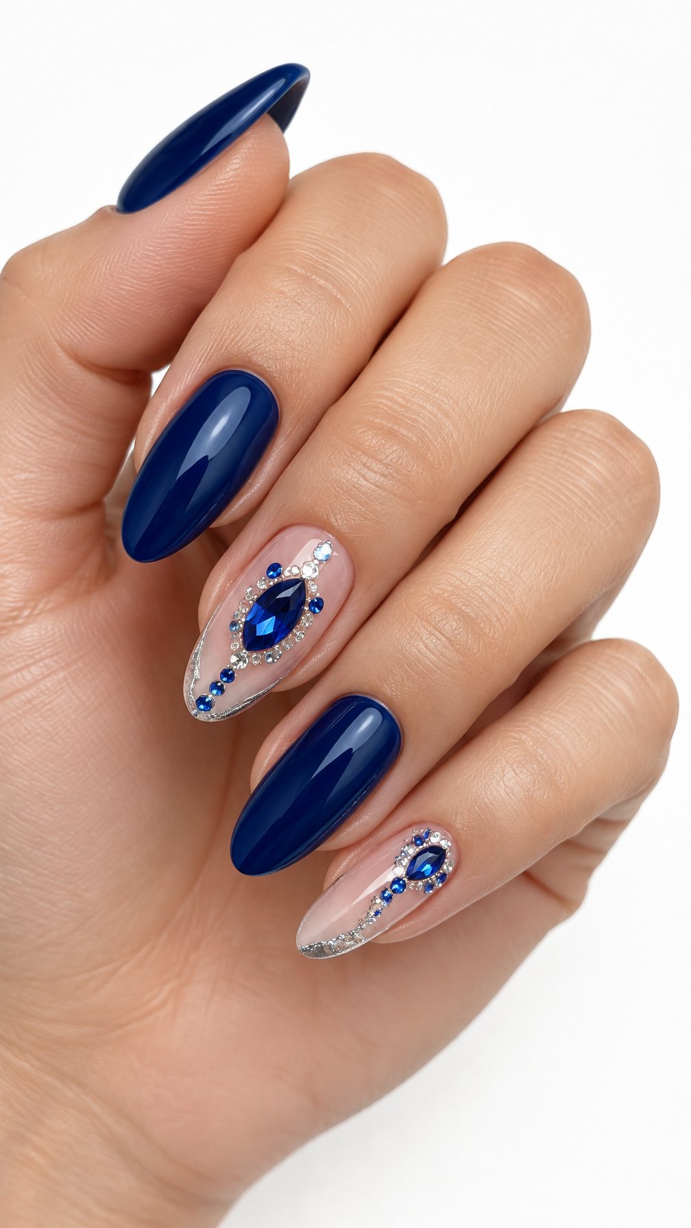 One hand with almond-shaped sapphire blue nails and gemstone-accented accent nails against a white background.